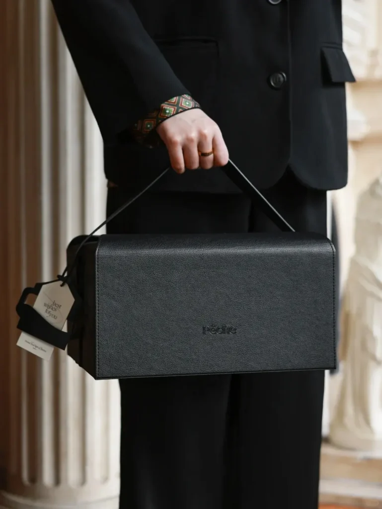Person holding a luxury black leather gift box containing high-end corporate gifts