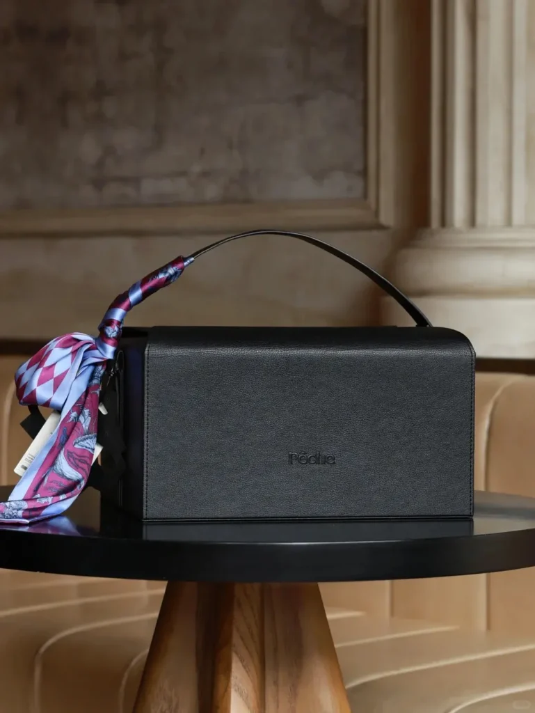 Close-up of luxury black leather gift box on a desk with high-end corporate gifts inside