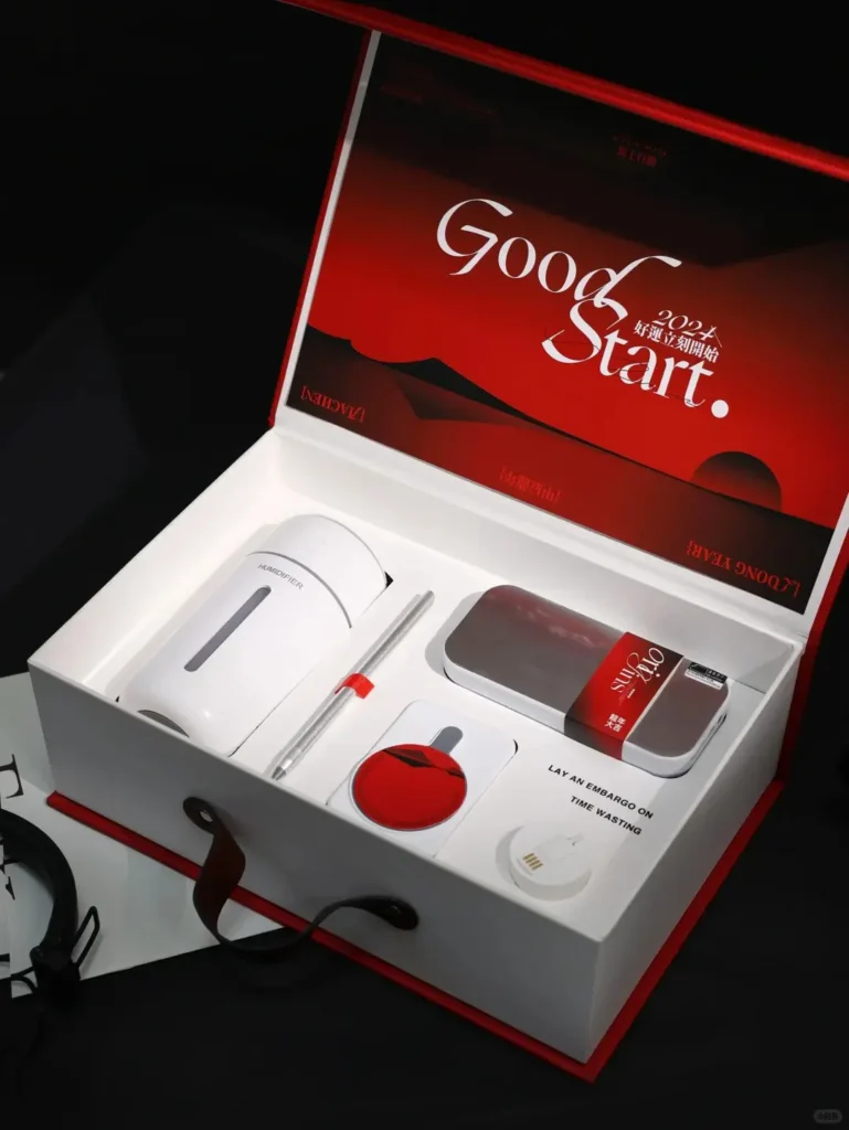 Red leather year-end corporate gift box with embossed logo, featuring Bluetooth speaker, 3-in-1 charging cable, magnetic wireless power bank, metal pen, and portable desktop humidifier. Perfect corporate gifts for employees.