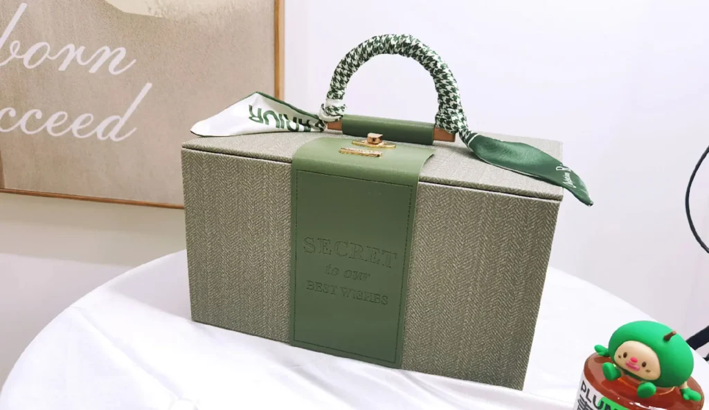 Elegant corporate gift box combining light green textile and olive leather craftsmanship displayed on a desk