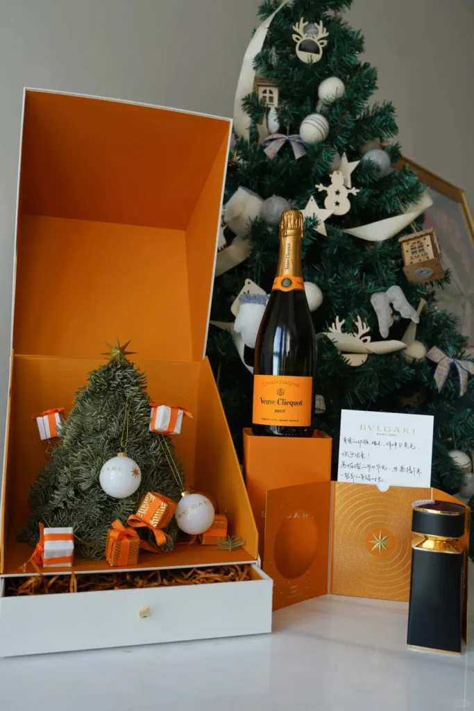 A festive corporate Christmas gift set featuring a Christmas tree, candy box, Veuve Clicquot champagne, and scented candle — a luxurious and cheerful holiday gift idea.