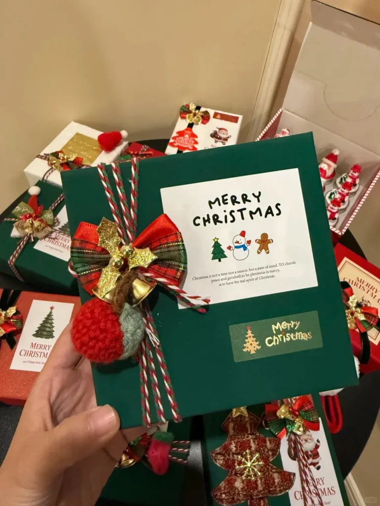 Employee holding and inspecting a green Christmas gift box with "MERRY CHRISTMAS" printed on it