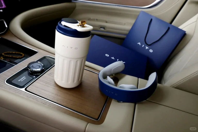 Aito customer appreciation gift box with neck massager and cup displayed on car armrest, packaging box and bag on passenger seat