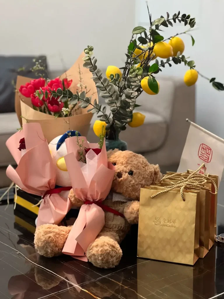 Employee 10 year anniversary gift featuring a teddy bear, gold coin gift box, and rose displayed on a tabletop.
