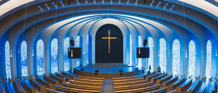 A warm church interior scene used as the cover image for an article about custom religious gifts at conference scale, highlighting faith-focused gifting for Christian events, churches, and ministries.
