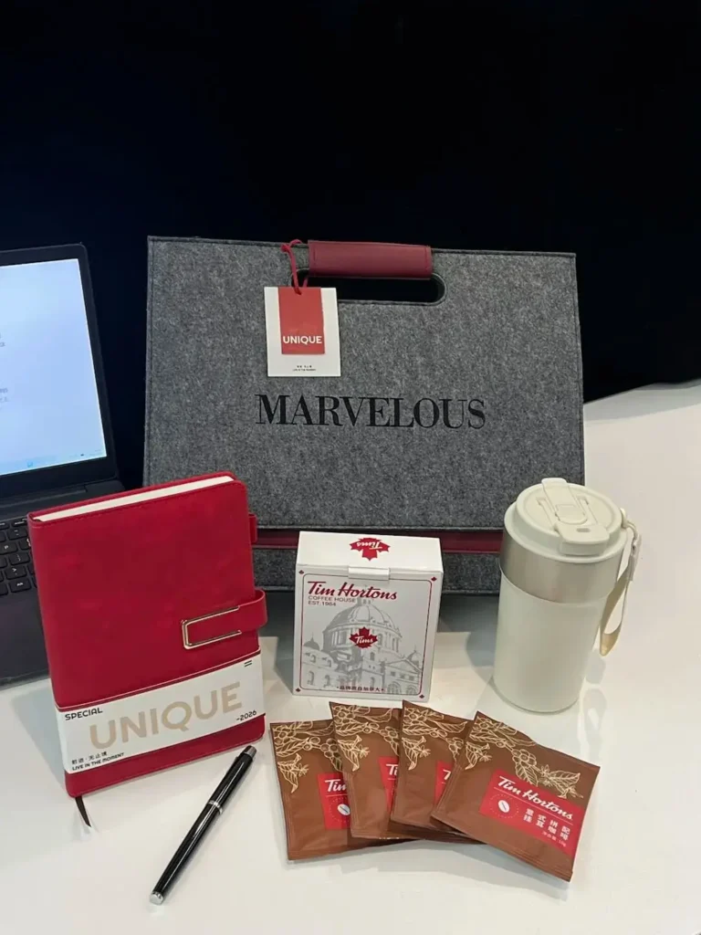 Company swag ideas for employees showing a gift set with drip coffee, coffee mug, pen and notebook on a desk