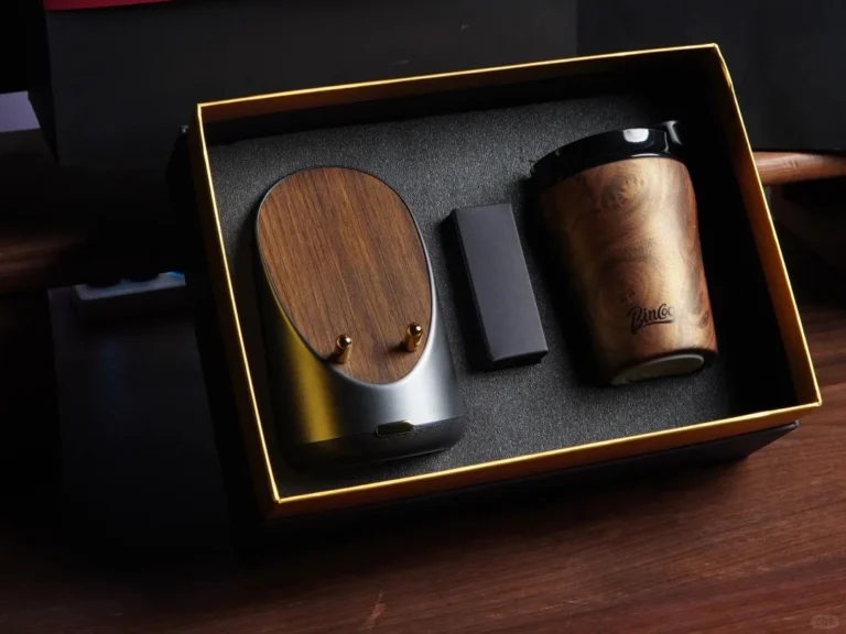Company swag ideas featuring a premium black and gold gift box with a wood grain coffee mug and matching Bluetooth speaker